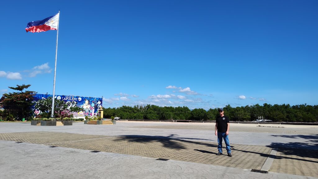 Picture from Lapu Lapu Monument showing the Philippine flag waving in the wind, blue sky.